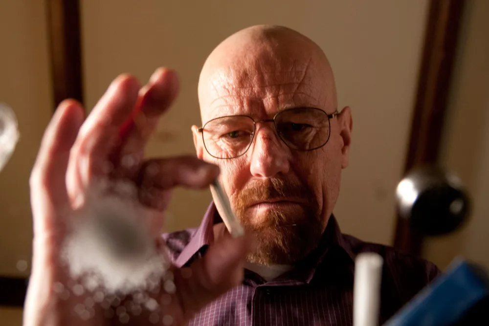 "Walter White in iconic yellow hazmat suit with intense look holding a chemistry flask"