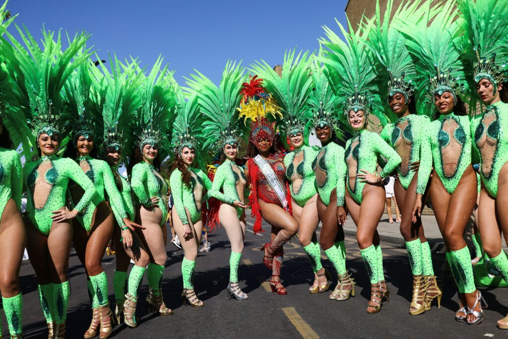 Colorful parade with dancers in costumes during Notting Hill Carnival in London.