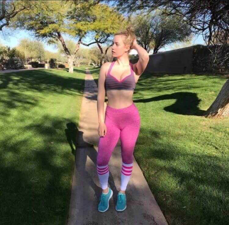Paige Spiranac swinging a golf club for the first time at a driving range.