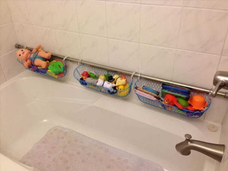 Tension rod installed along the bathtub wall holding baskets or containers filled with kids’ bath toys and supplies.