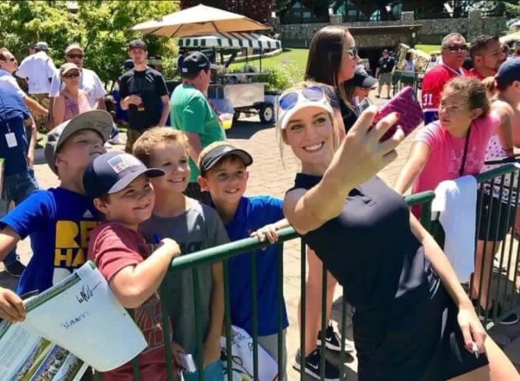 Paige Spiranac at a press conference surrounded by cameras and media attention.