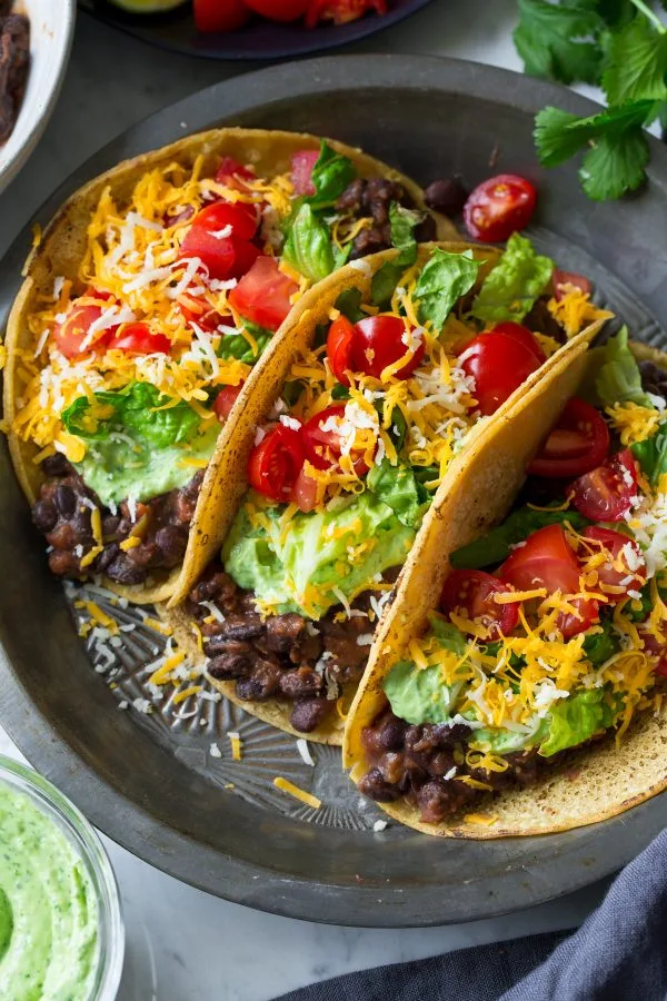 “Soft corn tacos filled with black beans, avocado slices, and salsa.”