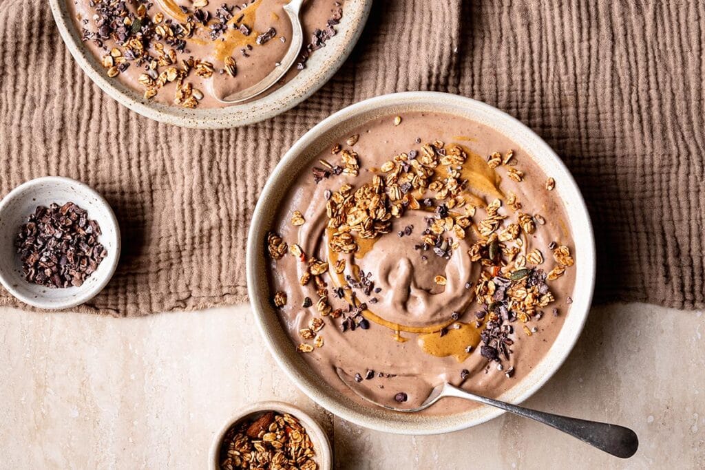 “Chocolate peanut butter smoothie bowl with banana slices, dark chocolate, and crushed peanuts on top.”