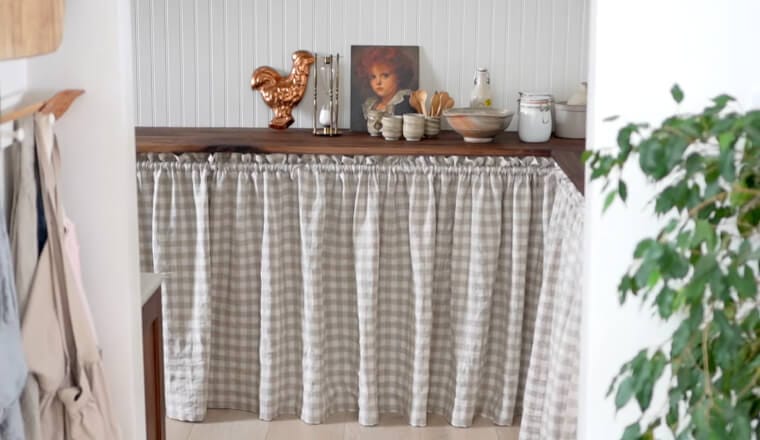 A table with a curtain skirt hanging from a tension rod, hiding storage or the table’s base to enhance room aesthetics.