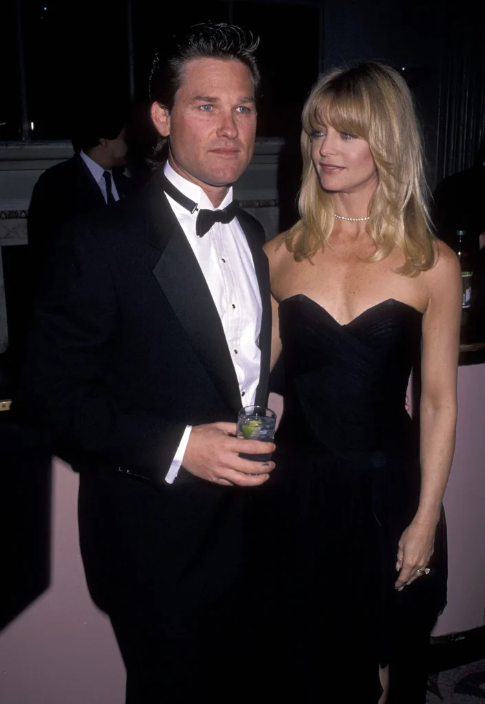“Goldie Hawn and Kurt Russell laughing together outdoors, showcasing their joyful and lasting relationship.”
