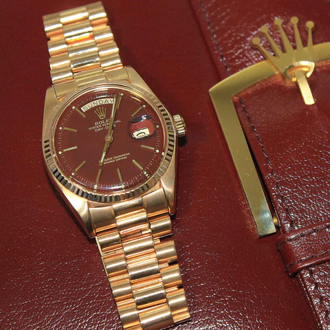 “Rihanna wearing a gold Rolex watch at a fashion event.”