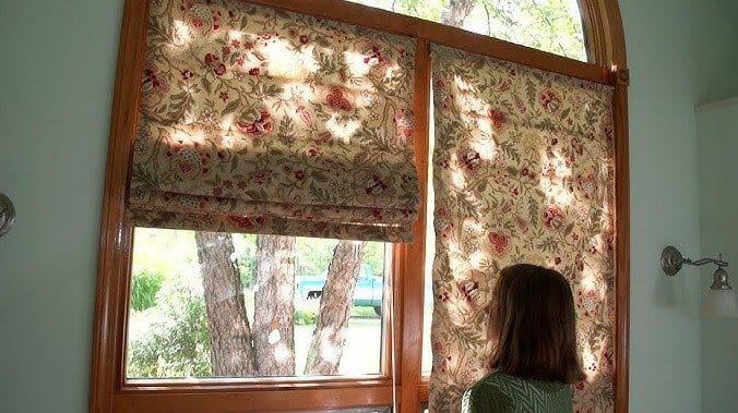 Window with fabric layered over multiple tension rods, creating a DIY Roman shade for privacy and style.