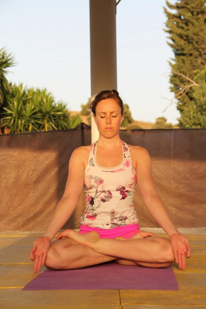 Woman meditating outdoors for stress relief and glowing skin.”