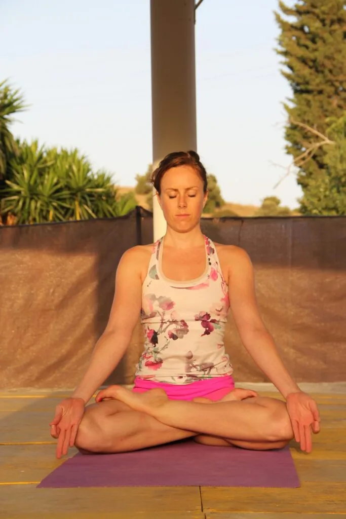 Woman meditating outdoors for stress relief and glowing skin.”