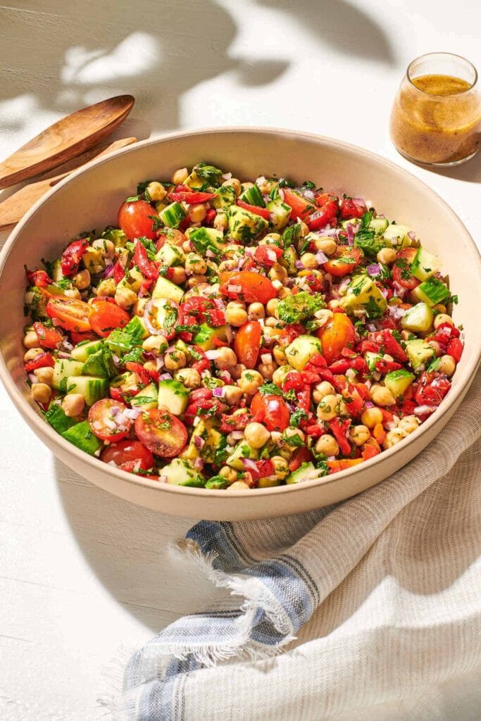 “Bowl of Mediterranean chickpea salad with tomatoes, cucumber, onions, and feta cheese.”