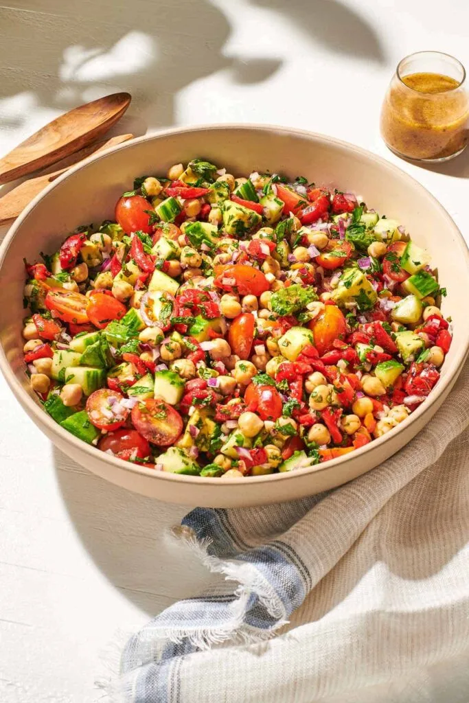 “Bowl of Mediterranean chickpea salad with tomatoes, cucumber, onions, and feta cheese.”