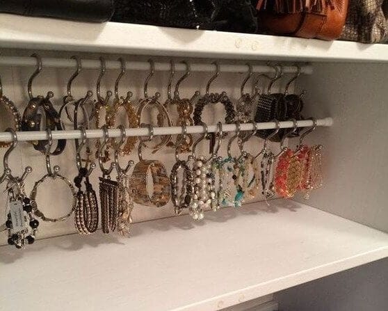 Tension rod installed in a closet with scarves, belts, and necklaces hanging neatly on hooks or clips.