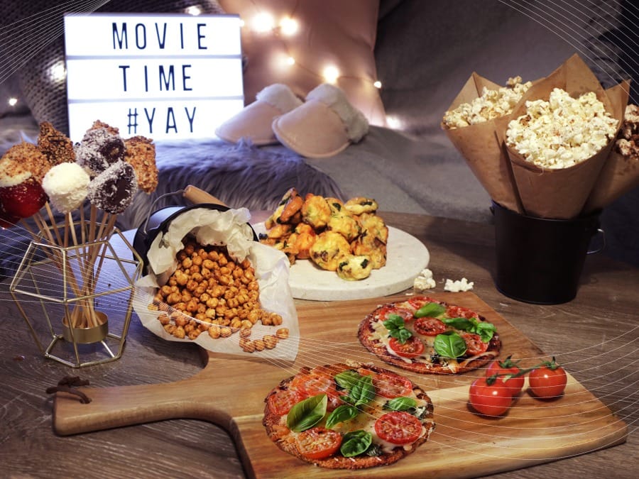 “Table filled with themed movie snacks like popcorn, candy, and mocktails.”