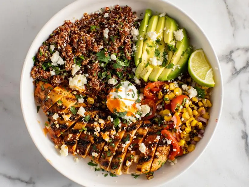 “Healthy quinoa bowl topped with grilled chicken, spinach, and shredded carrots.”