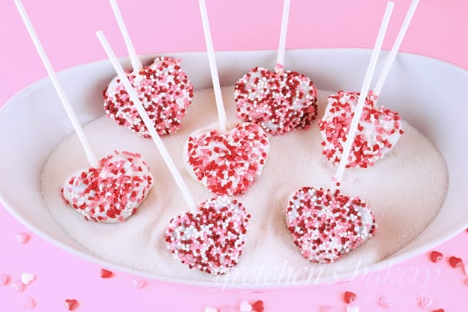“Heart-shaped red velvet cake pops dipped in chocolate with red ribbons for Valentine’s gift”