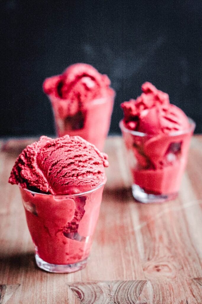 “Homemade red velvet ice cream with cake crumbs and chocolate syrup served in bowls”