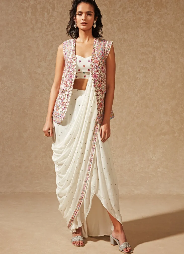 Woman wearing a sari with a tailored embroidered blazer, blending Indian and Western formal fashion.