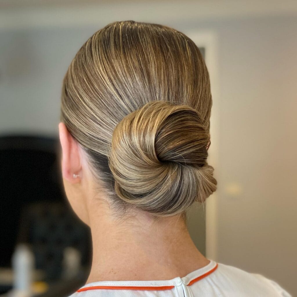 Woman wearing a sleek high bun hairstyle to prevent frizz in humid summer weather — Best Hairstyles to Beat Summer Humidity.