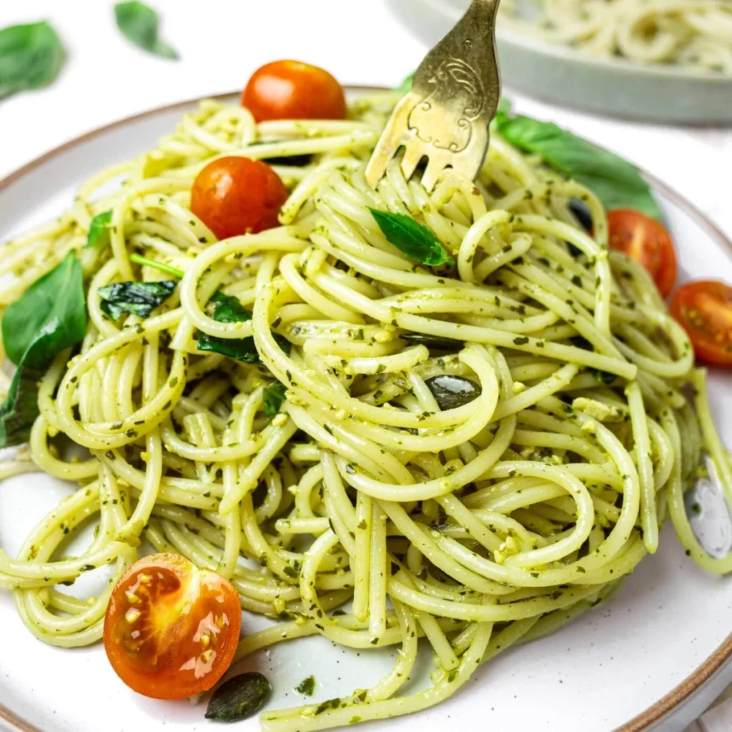 “Fresh spaghetti al pesto Genovese with basil, pine nuts, and olive oil – authentic Italian pasta dish for home cooking.”