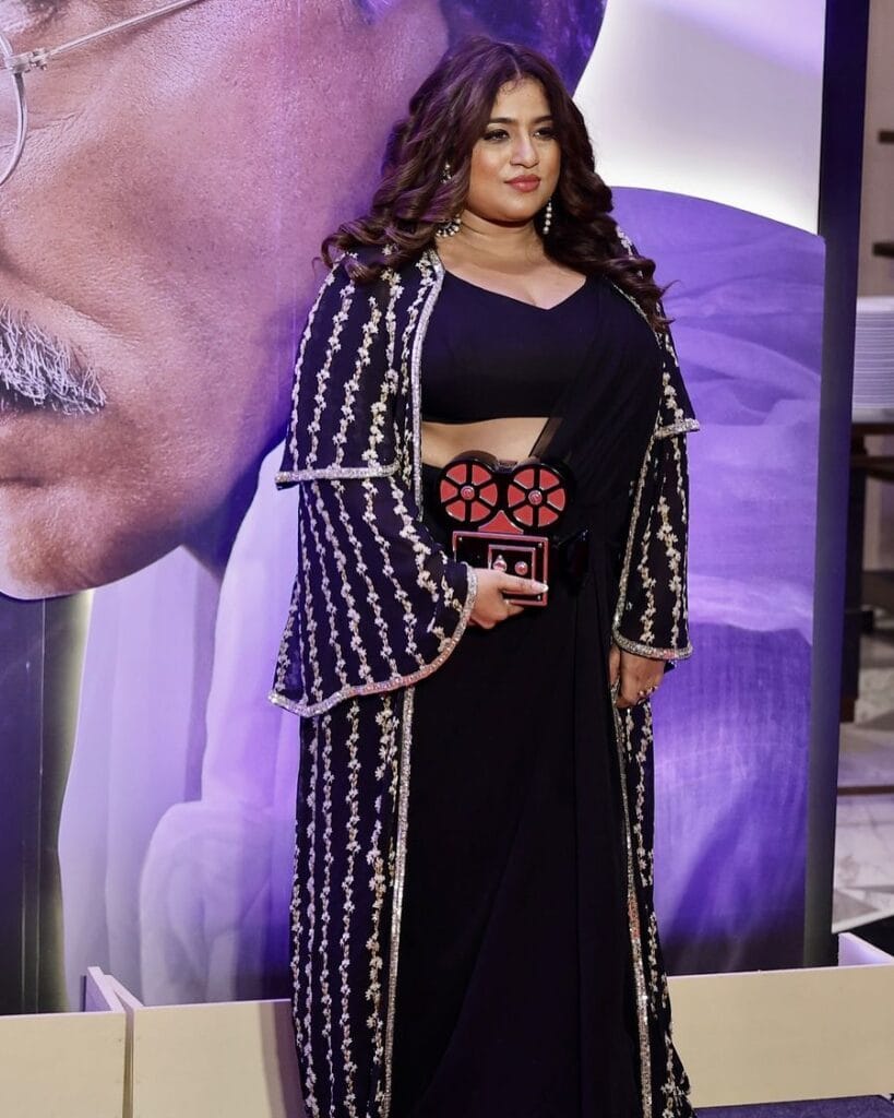 Elegant sari outfit with a sheer embroidered cape overlay, replacing traditional jewelry for a modern glam look.