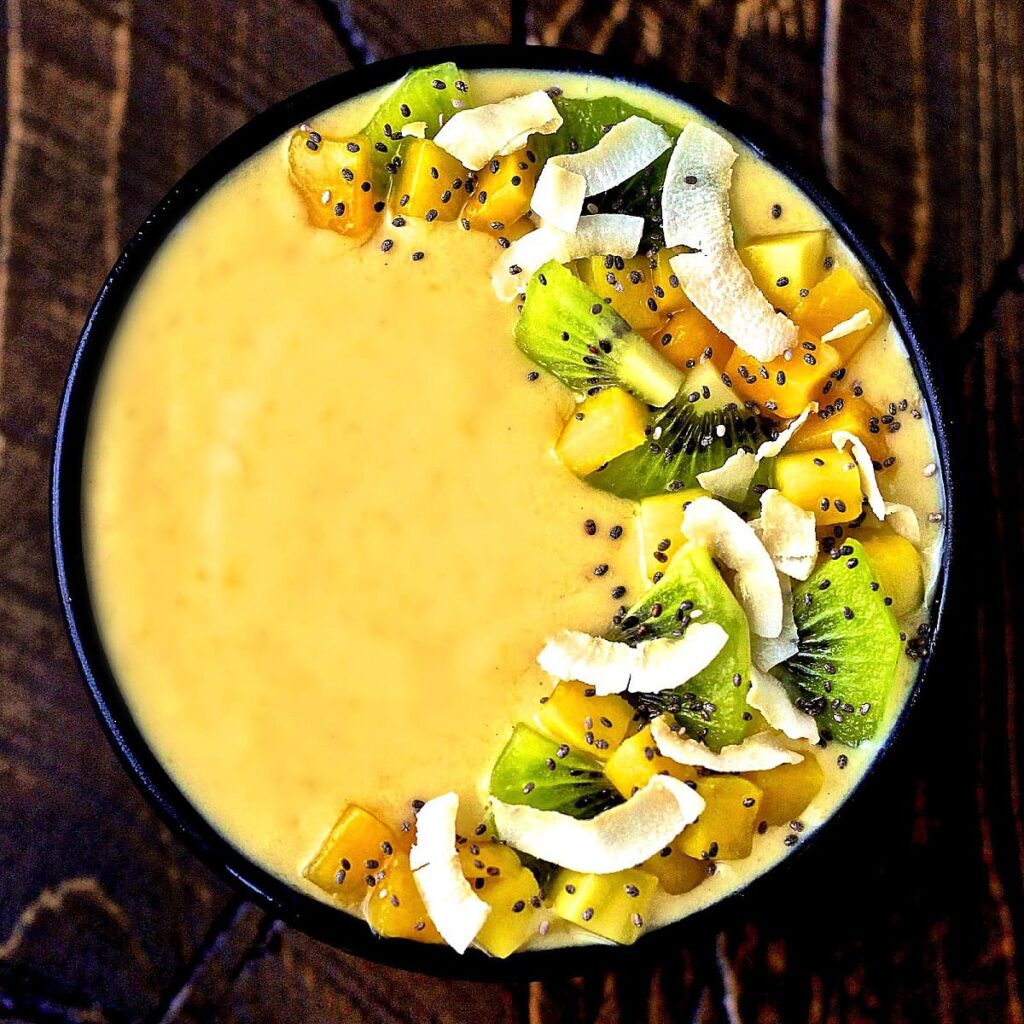 “Tropical smoothie bowl with mango, pineapple, banana, and coconut toppings served in a white bowl.”