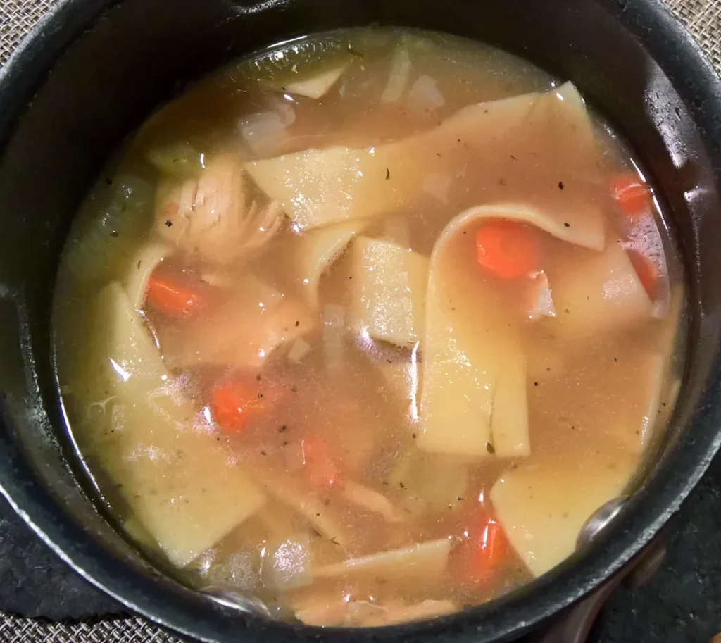 A modern Instant Pot on a kitchen counter surrounded by winter vegetables like carrots, potatoes, and onions.