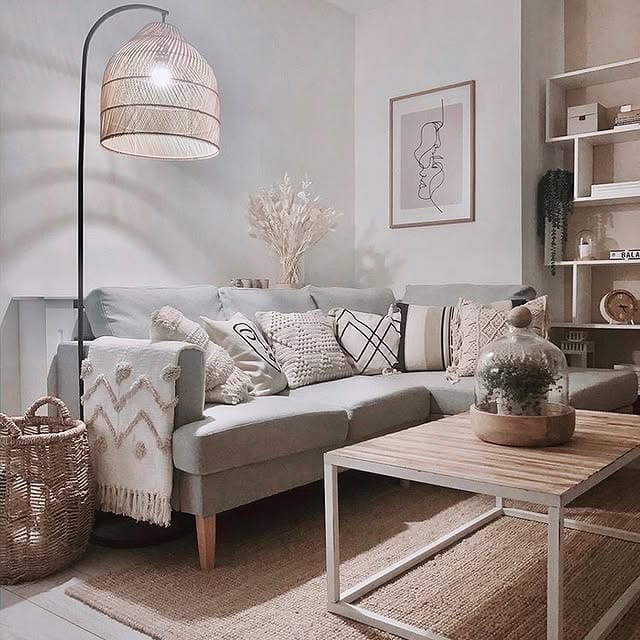 Cozy boho living room featuring a curved floor lamp with a rattan shade, neutral pillows, woven basket, and jute rug.