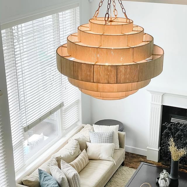 Modern living room featuring a tiered rattan chandelier above a minimalist fireplace and neutral furniture.