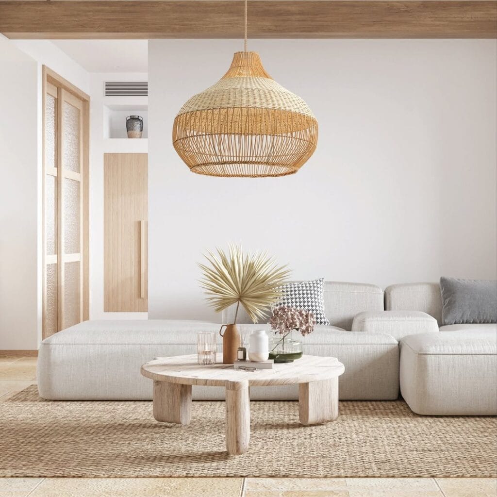 Minimalist living room with an open-weave rattan pendant light, jute rug, neutral sectional, and rustic wood coffee table.
