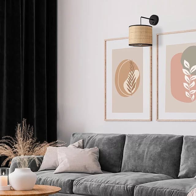 Modern minimalist living room with a rattan wall sconce, velvet sofa, black frame accents, and simple wall art.