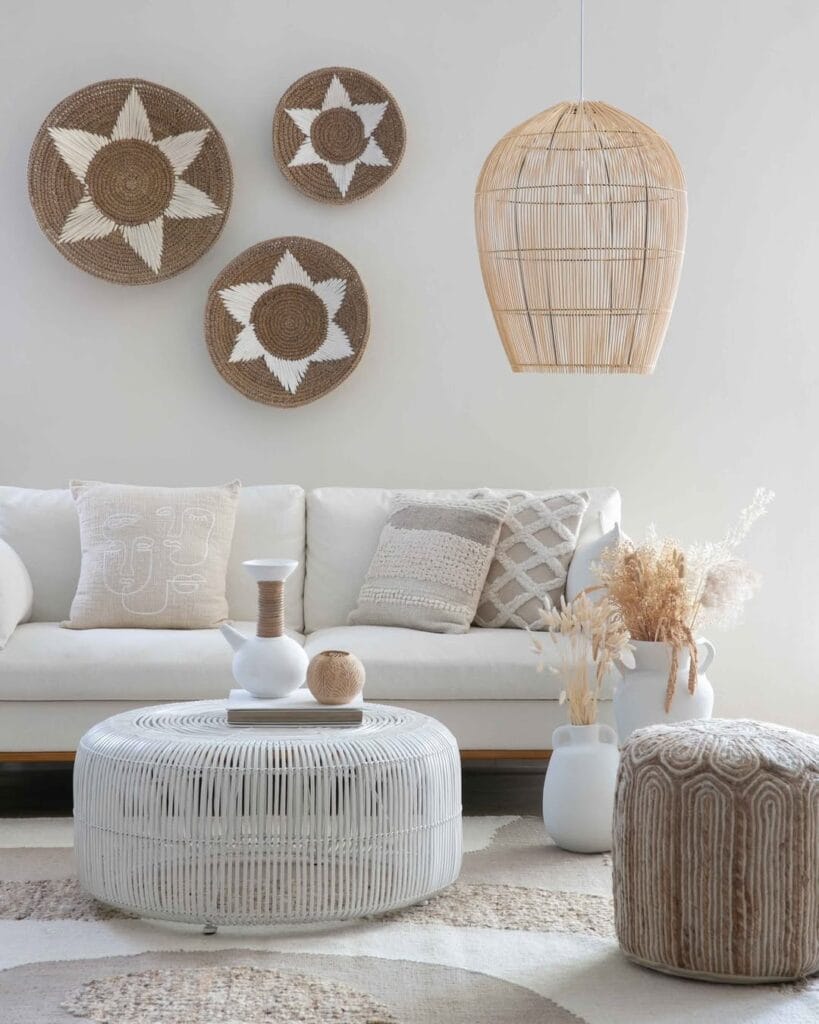 Light and airy living room with a rattan pendant light, woven wall decor, tufted pouf, and organic neutral furnishings.