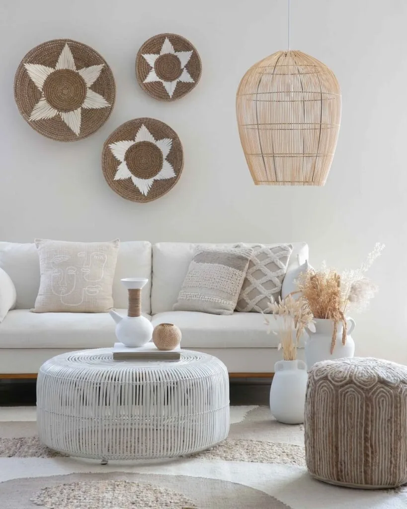 Light and airy living room with a rattan pendant light, woven wall decor, tufted pouf, and organic neutral furnishings.