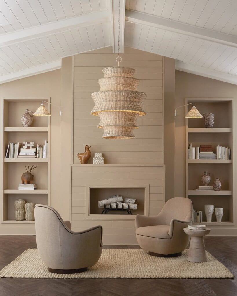 Neutral living room with a layered rattan pendant light, curved armchairs, beige tones, and a textured woven rug.