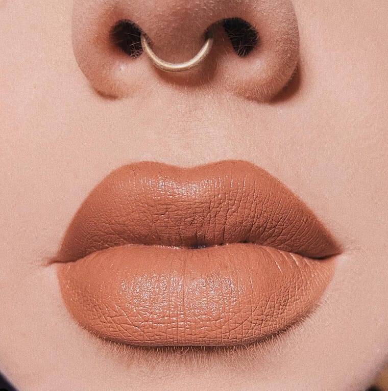 Woman applying lip liner carefully just along natural lip line for fuller lips.