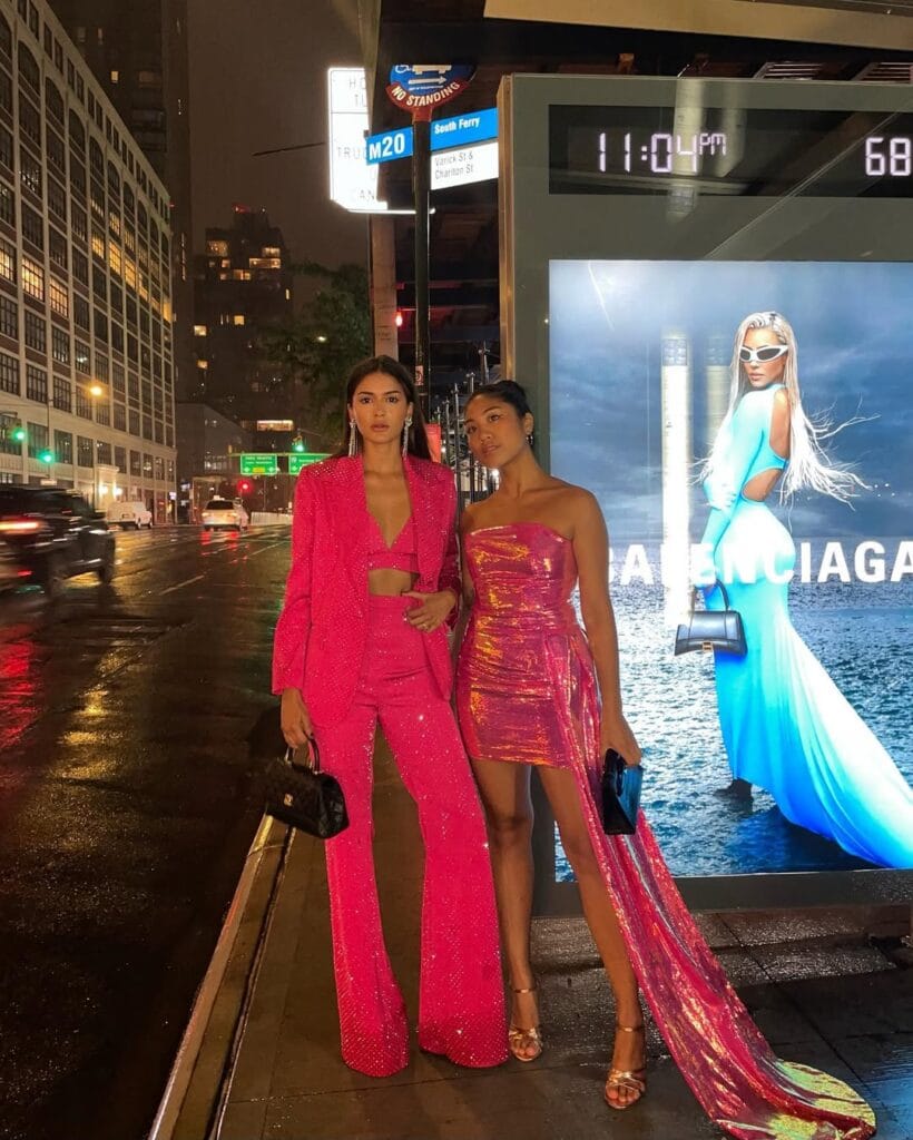 Hot pink glitter outfits including a sparkly suit with flared pants and a glitter mini dress with a train, styled with clutch bags and metallic heels.