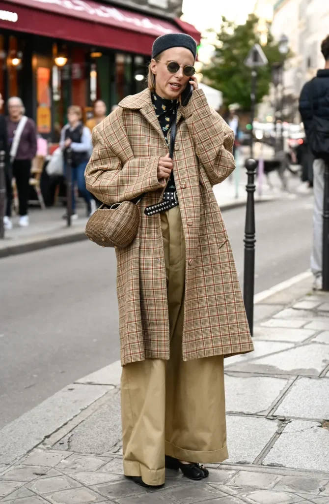 “Woman wearing a tailored trench coat layered over winter essentials during December.”